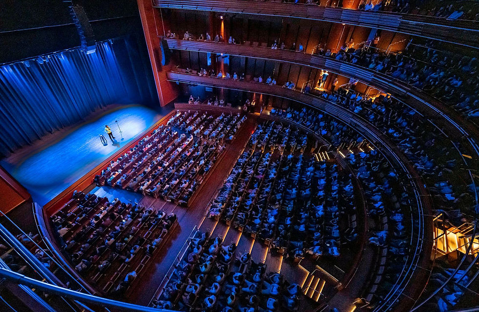 A full theater audience watching a live stage performance